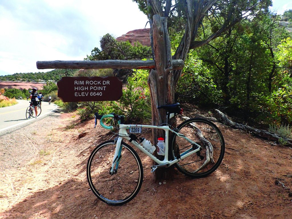 My bike leaning against the elevation sign at the highest point of the National Monument Grand Junction Colorado